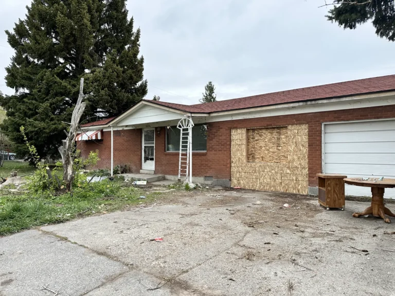Brick ranch house with a boarded-up window and garage