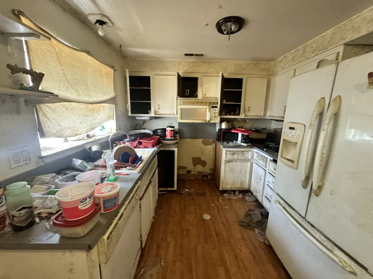 Dated kitchen with counters covered in dishes and boxes