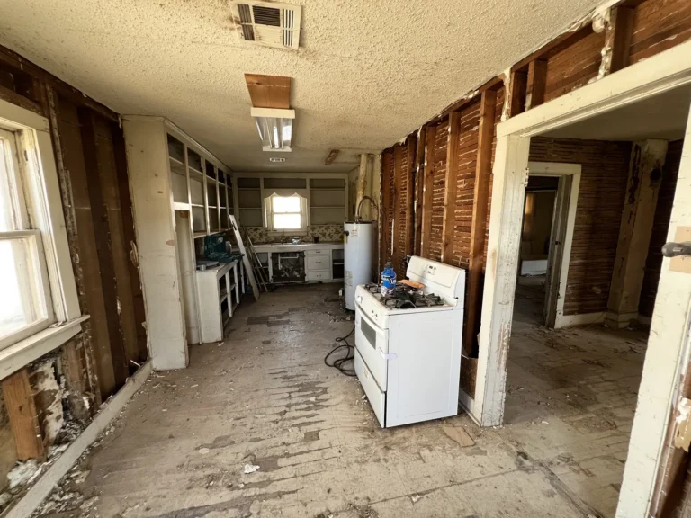 Gutted kitchen with an old stove and stripped walls