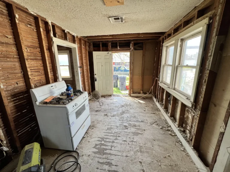 Room stripped to the studs with windows letting in light
