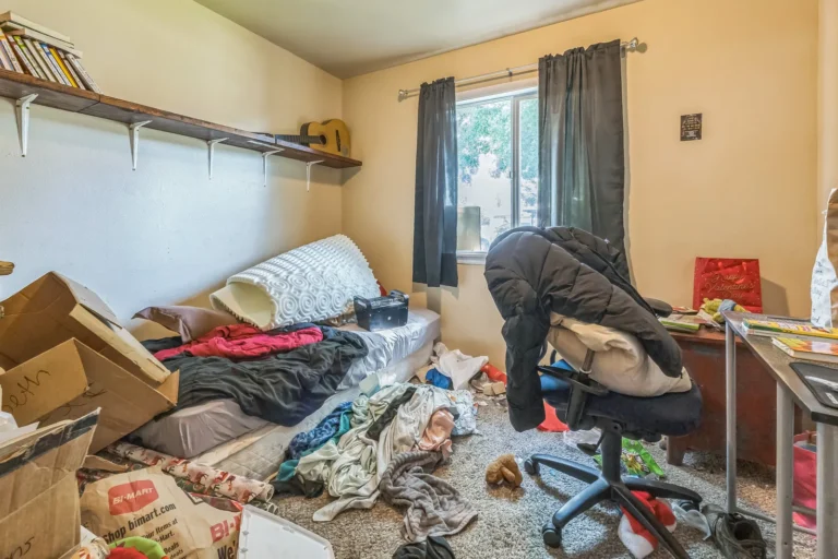 Bedroom filled with clothes and belongings before a cleanout