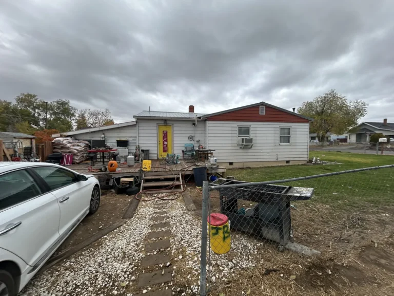 Older house with a gravel driveway and cluttered yard