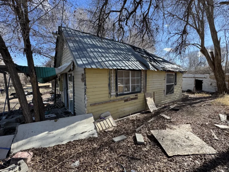 Old house with broken siding and boards in the yard